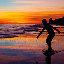 A man skating on the beach along with sunset